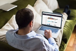 Un homme consulte un site de crowdlending confortablement installé sur un canapé Un homme consulte un site de crowdlending confortablement installé sur un canapé